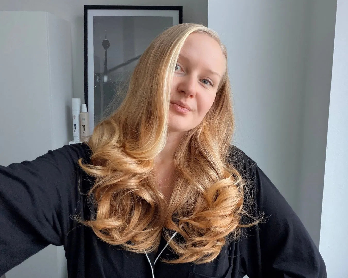 Frau mit Locken und blonden, langen Haaren macht Selfie