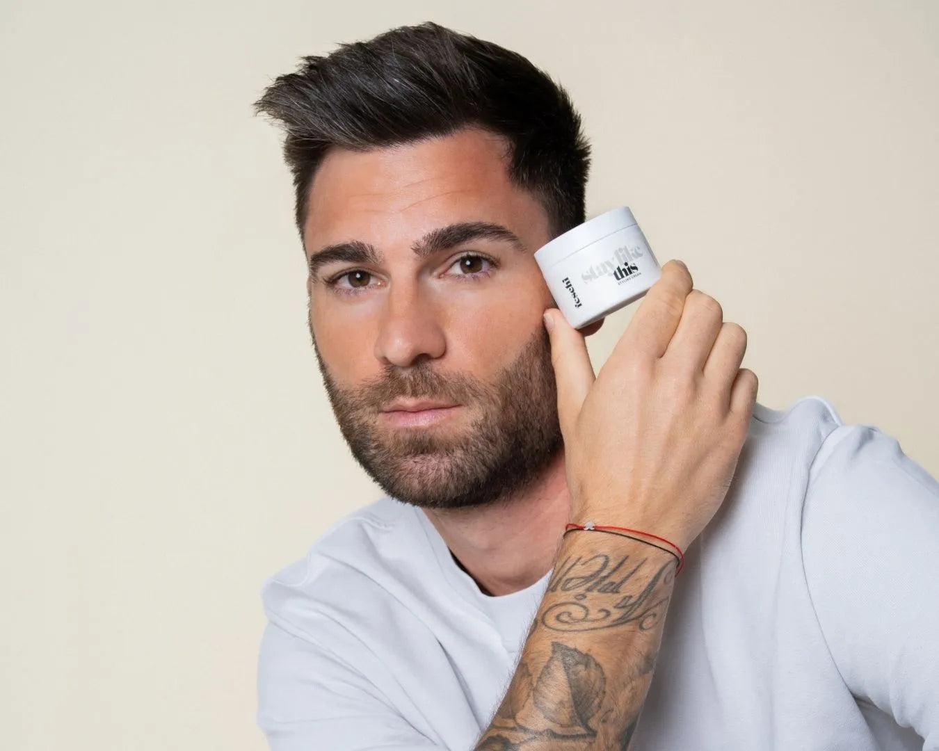 Mann mit braunen Haaren hält die feschi Stay Like This Styling Cream in der Hand