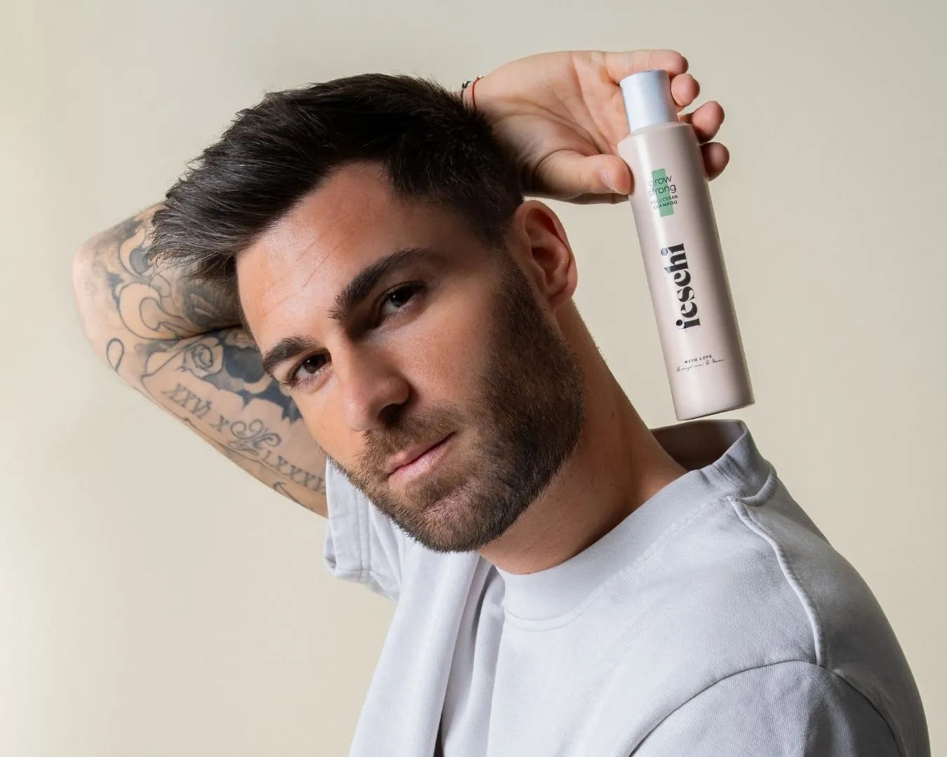 Ein Mann hält das grow strong - Follicusan Shampoo von feschi hinter seinem Kopf und blickt in die Kamera
