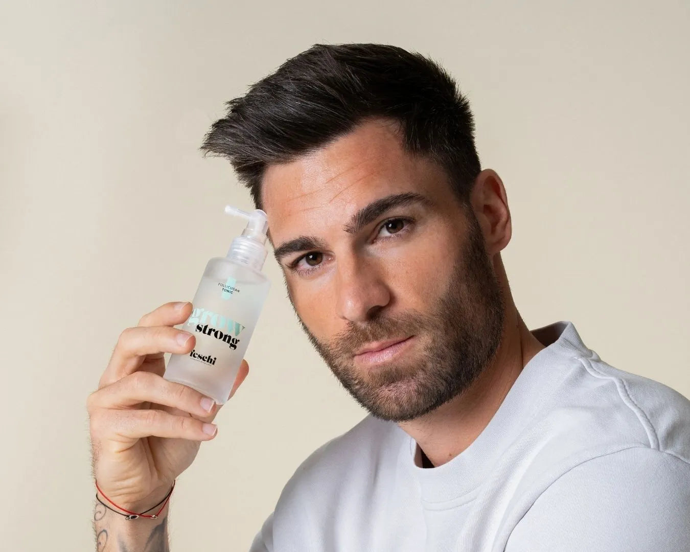 Mann hält das grow strong Tonic von feschi in der Hand