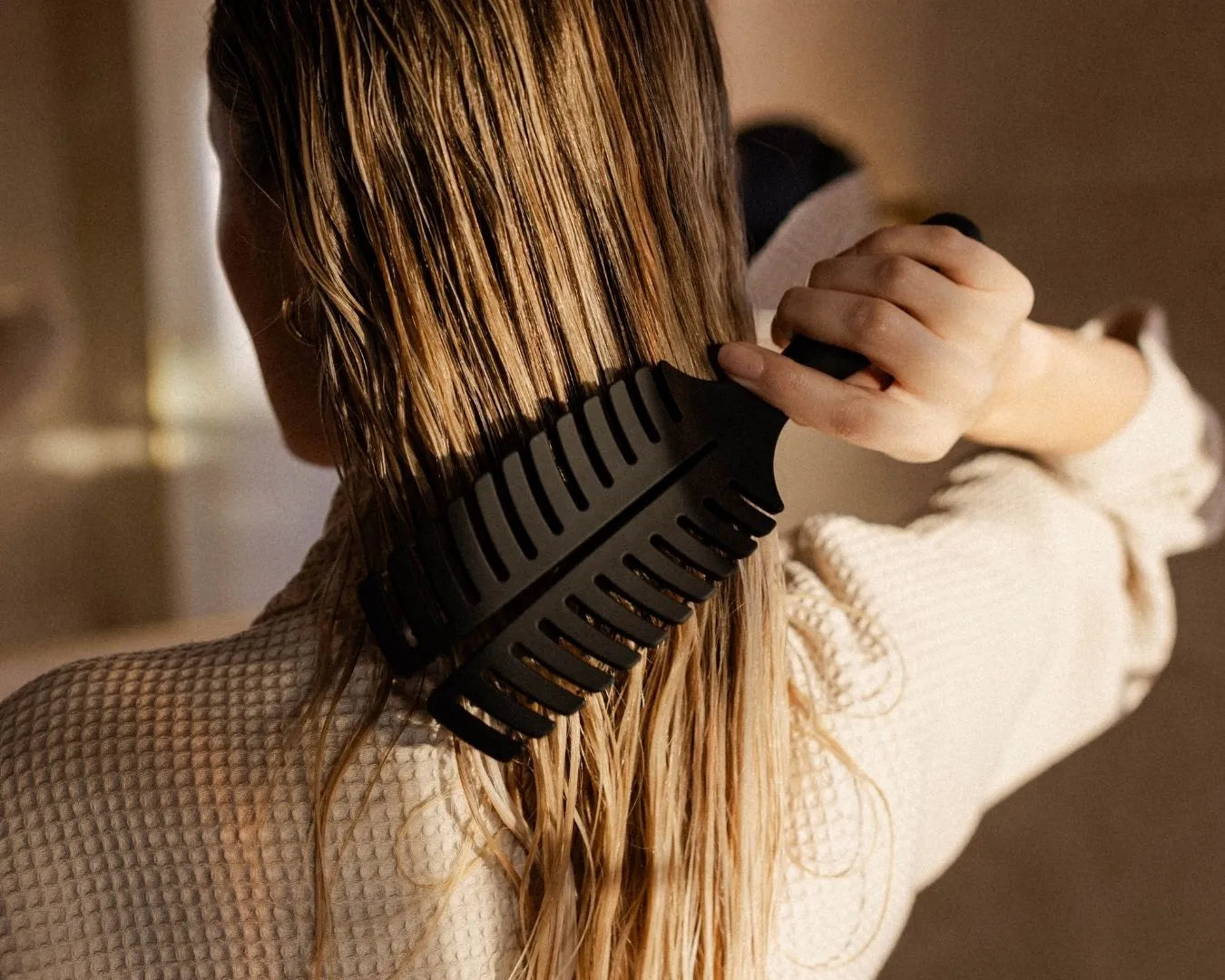 Person von hinten, die sich die nassen Haare kämmt