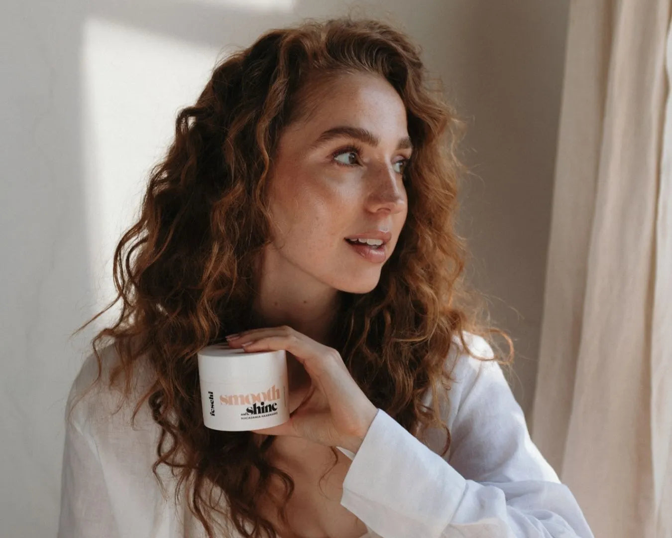 Frau mit roten Locken hält Macadamia Maske von feschi in der Hand