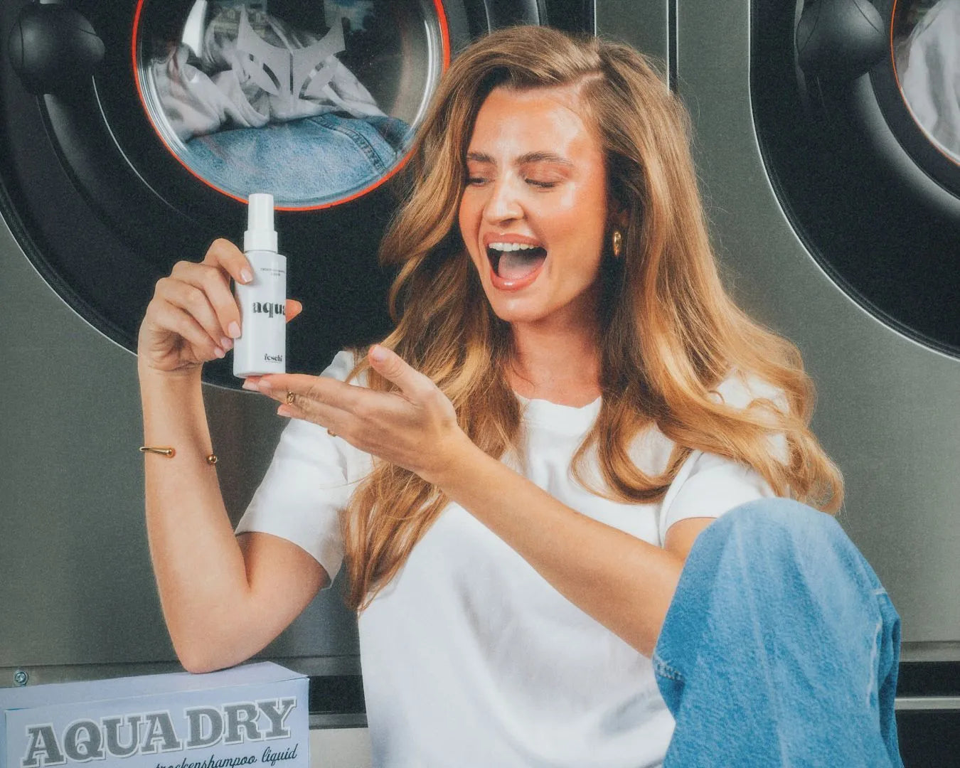 Frau mit frischen, voluminösen Haaren hält das Trockenshampoo Liquid von feschi in der Hand