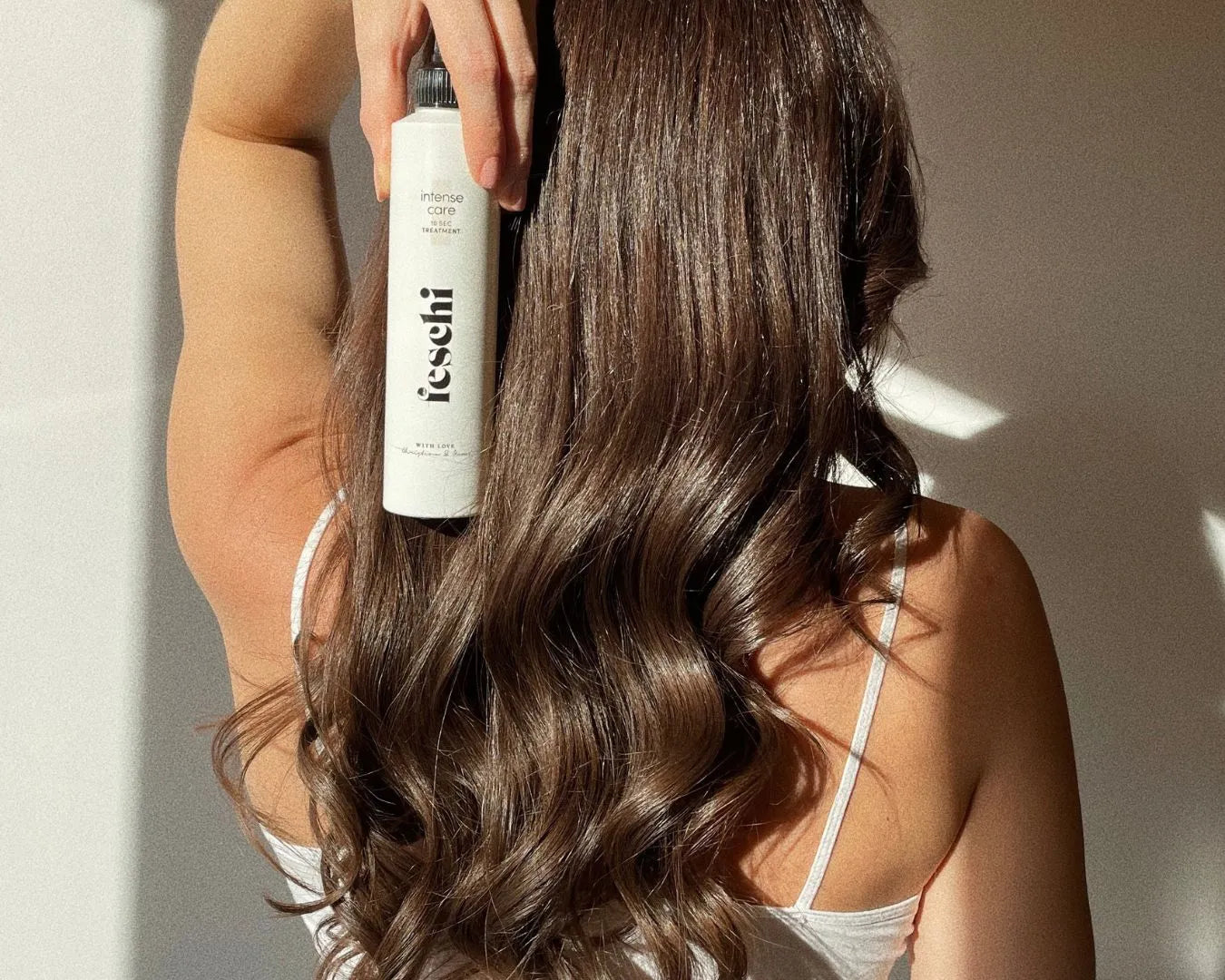 Person mit langen braunen lockigen Haaren die wunderschön glänzen hält intense care - 10 second treatment von feschi in der hand