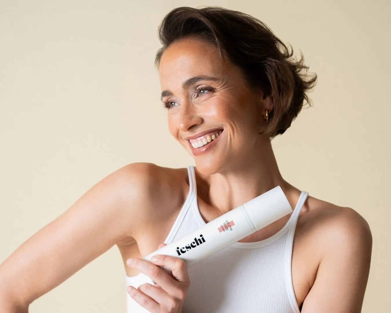 Frau hält Volumen Mousse von feschi in der Hand und lächelt