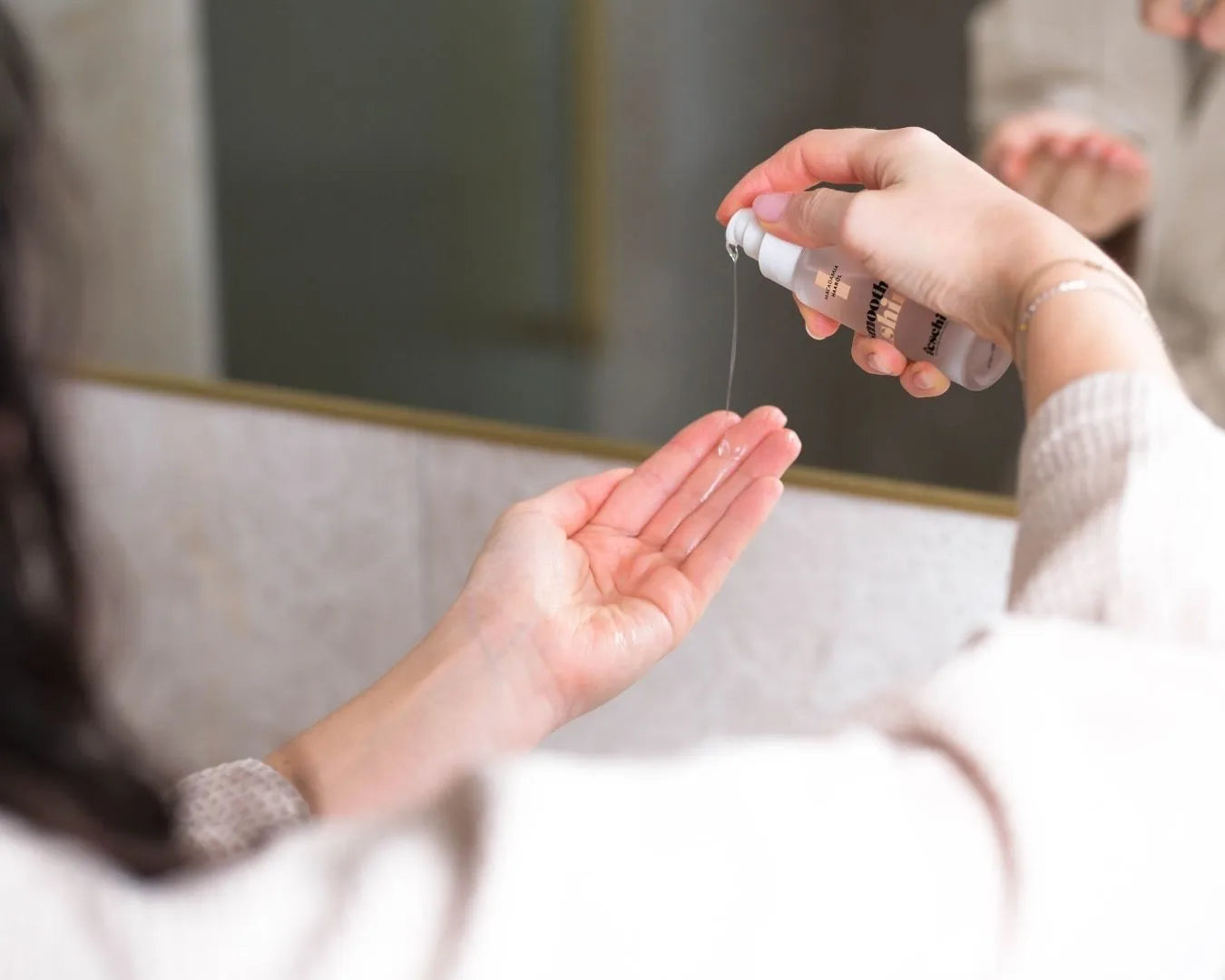Weibliche Hände, eine Hand hält das feschi Smooth & Shine Haaröl und drückt das Produkt in die andere Hand