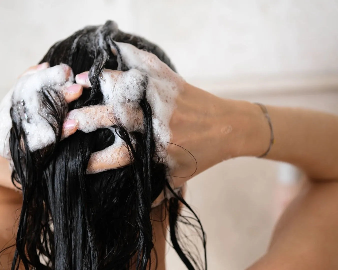 Person schäumt sich gerade ein Produkt in den Haaren auf