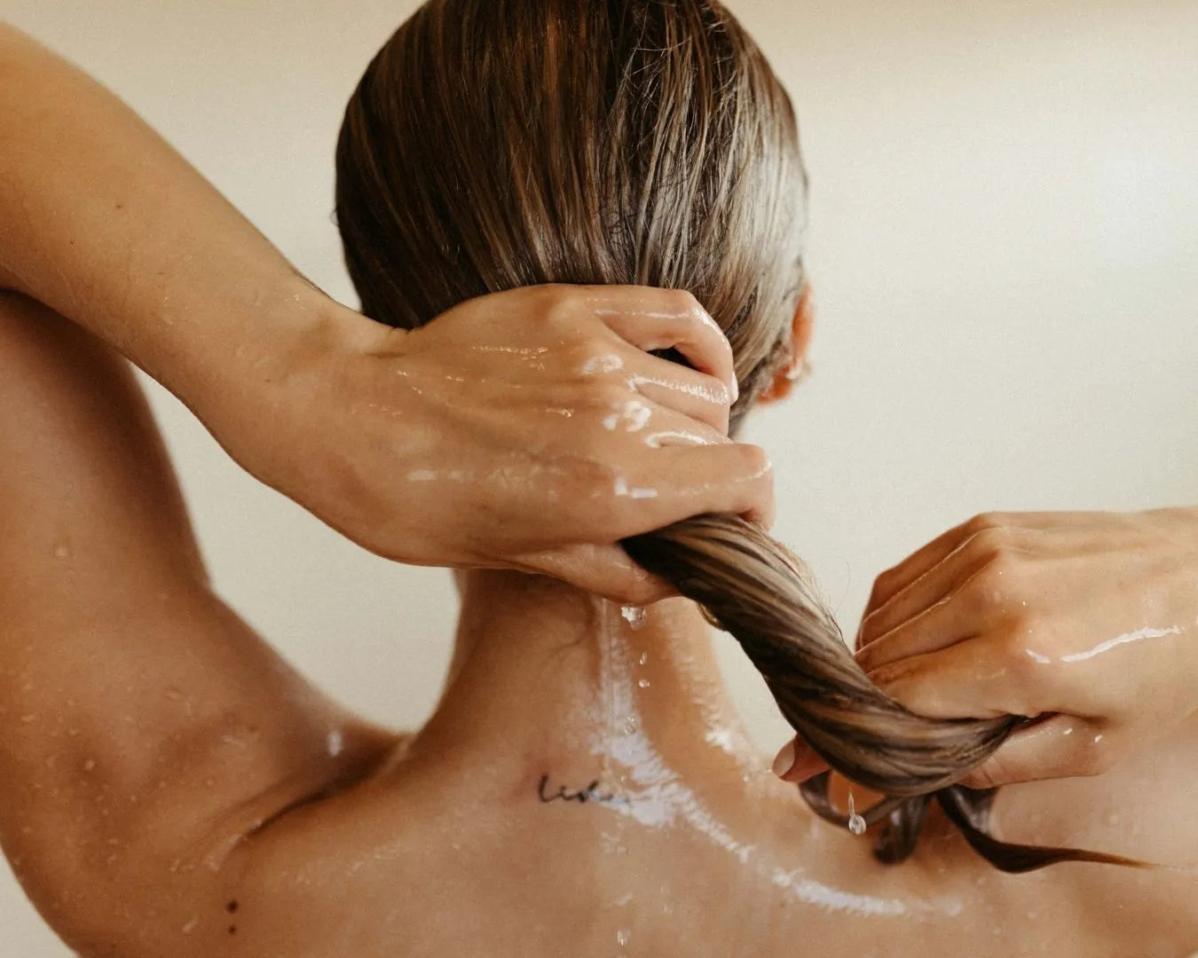 Person von hinten, die sich die nassen Haare hält