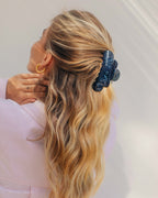 Frau mit langen, lockigen blonden Haaren und blauer Haarspange
