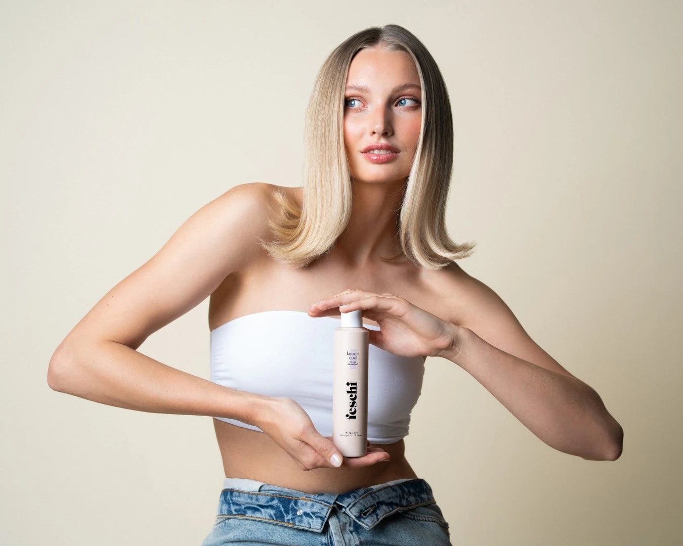 Frau mit blonden Haaren und weißem Top hält das Silbershampoo von feschi in der Hand und blickt auf die Seite