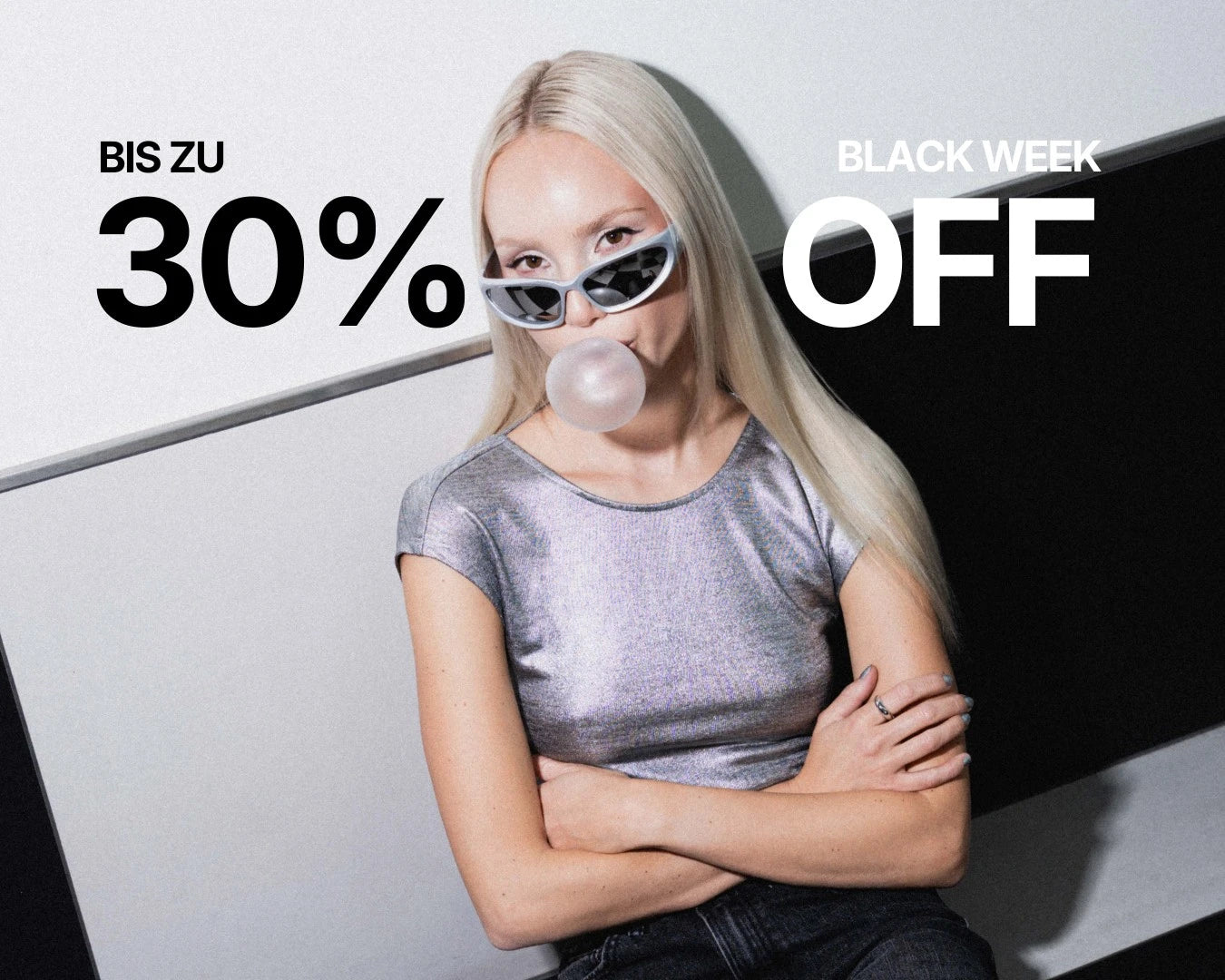 Frau lehnt an karierter Wand und macht eine Kaugummi-Blase, sie hat blondes platin gefärbtes Haar