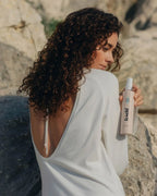 Rückansicht einer Frau mit Locken und feschi Curly Baby Lockenspray - perfekte Pflege für natürliches Volumen.