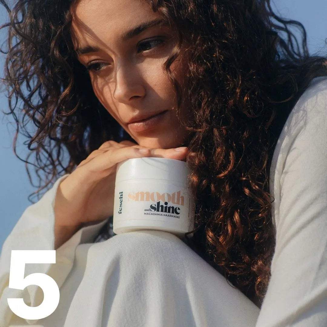 Frau von vorne mit langen braunen Locken hält die feschi Smooth & Shine Haarmaske in der Hand