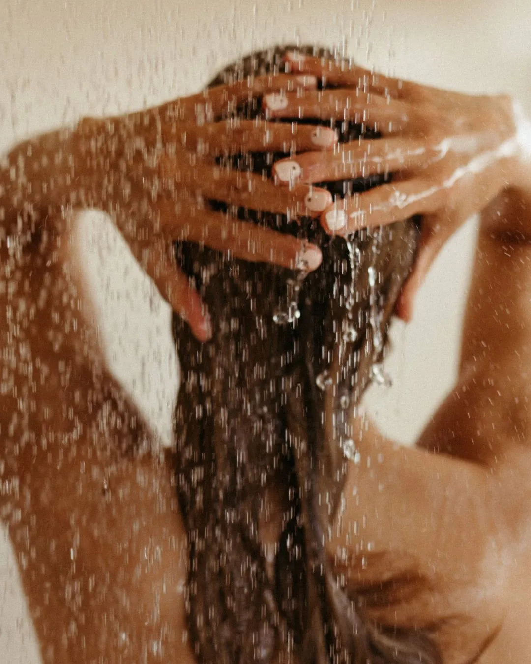 Frau von hinten unter der Dusche, wäscht ihre Haare