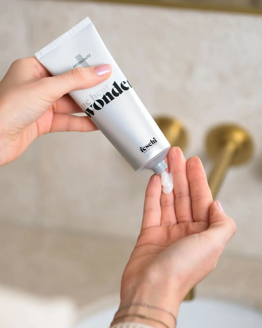 Zwei Hände, eine drückt Produkt aus dem feschi One Heat Wonder Hitzeschutz in die andere Hand