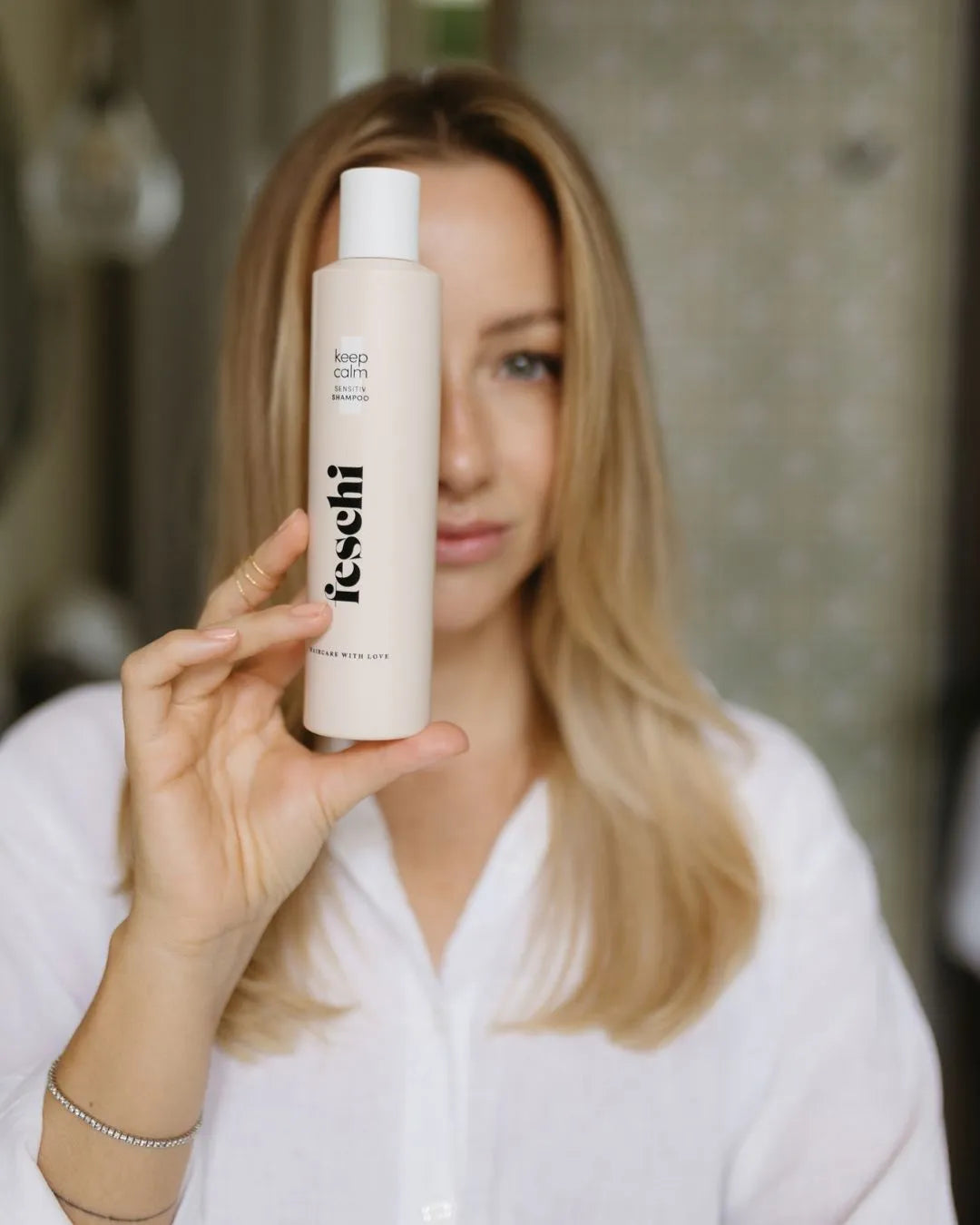 Christina Bischof hält feschi smooth&shine keep calm Shampoo vor ihrem Gesicht
