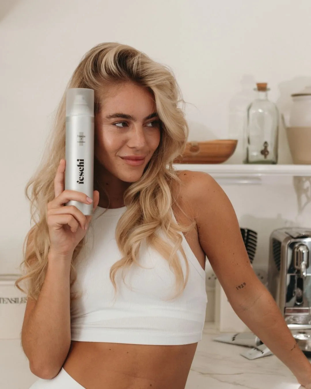 Blonde Frau mit Wellen frischt ihre Frisur mit feschi Freeze It Haarspray im Badezimmer auf