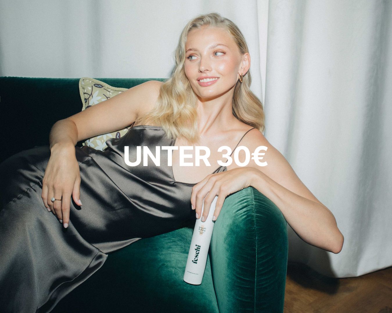 Frau halb liegend auf einem Sofa hält den feschi Smooth & Shine Anti-Frizz Spray in der Hand; darüber der Schriftzug ‚unter 30 €‘