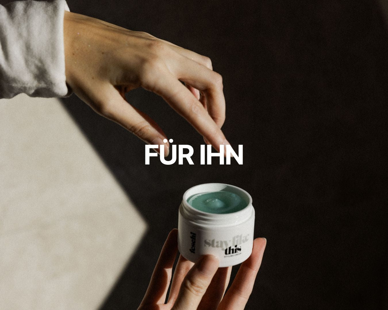 Zwei Hände, eine hält die feschi Stay Like This Styling Cream, die andere greift danach; darüber der Schriftzug ‚Für Ihn‘