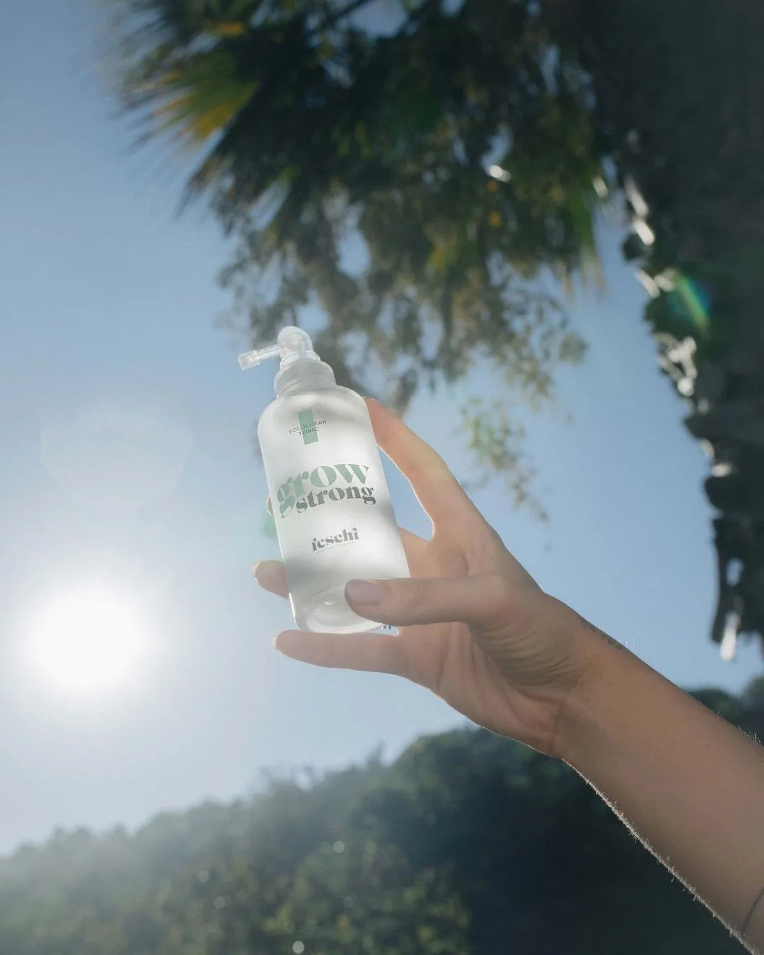Hand hält feschi Grow Strong Tonic im Sonnenlicht - natürliches Haarpflegeprodukt mit Follicusan