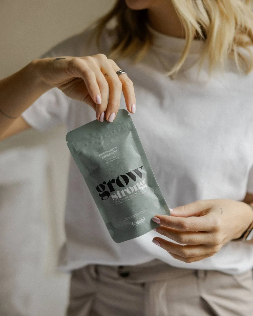 Frau hält feschi Grow Strong Nahrungsergänzungsmittel für gesundes Haarwachstum in der Hand