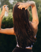 Frau mit braunen, langen Haaren von hinten, die gerade das grow strong Tonic verwendet
