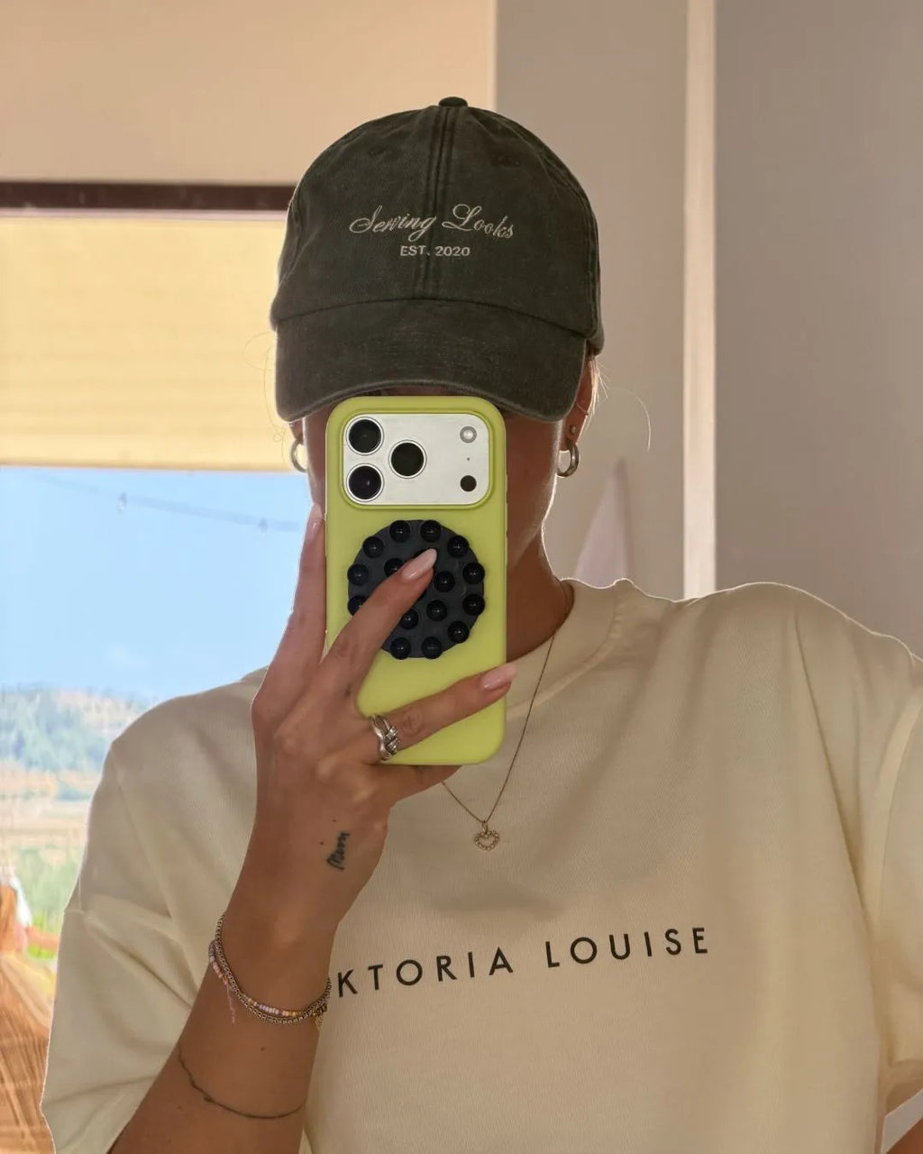 Person macht ein Spiegelfoto mit IPhone und trägt dabei eine Vintage Kappe von feschi