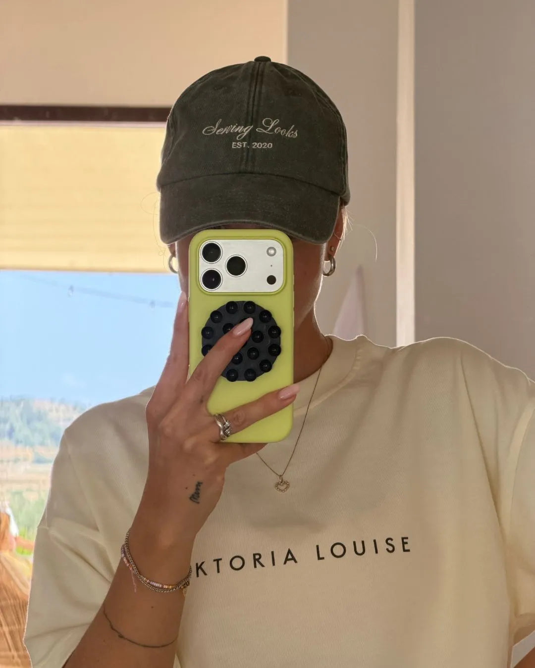 Person macht ein Spiegelfoto mit IPhone und trägt dabei eine Vintage Kappe von feschi