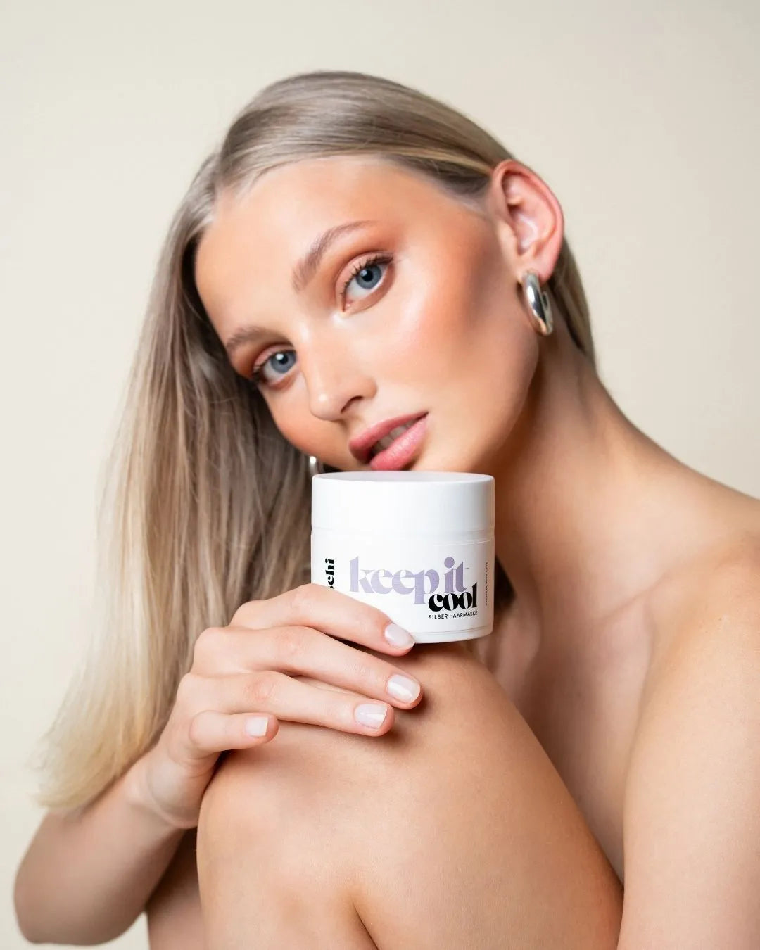 Frau mit hellblondem Haar präsentiert die feschi Keep It Cool Silber Maske – Anti-Gelbstich Haarpflege