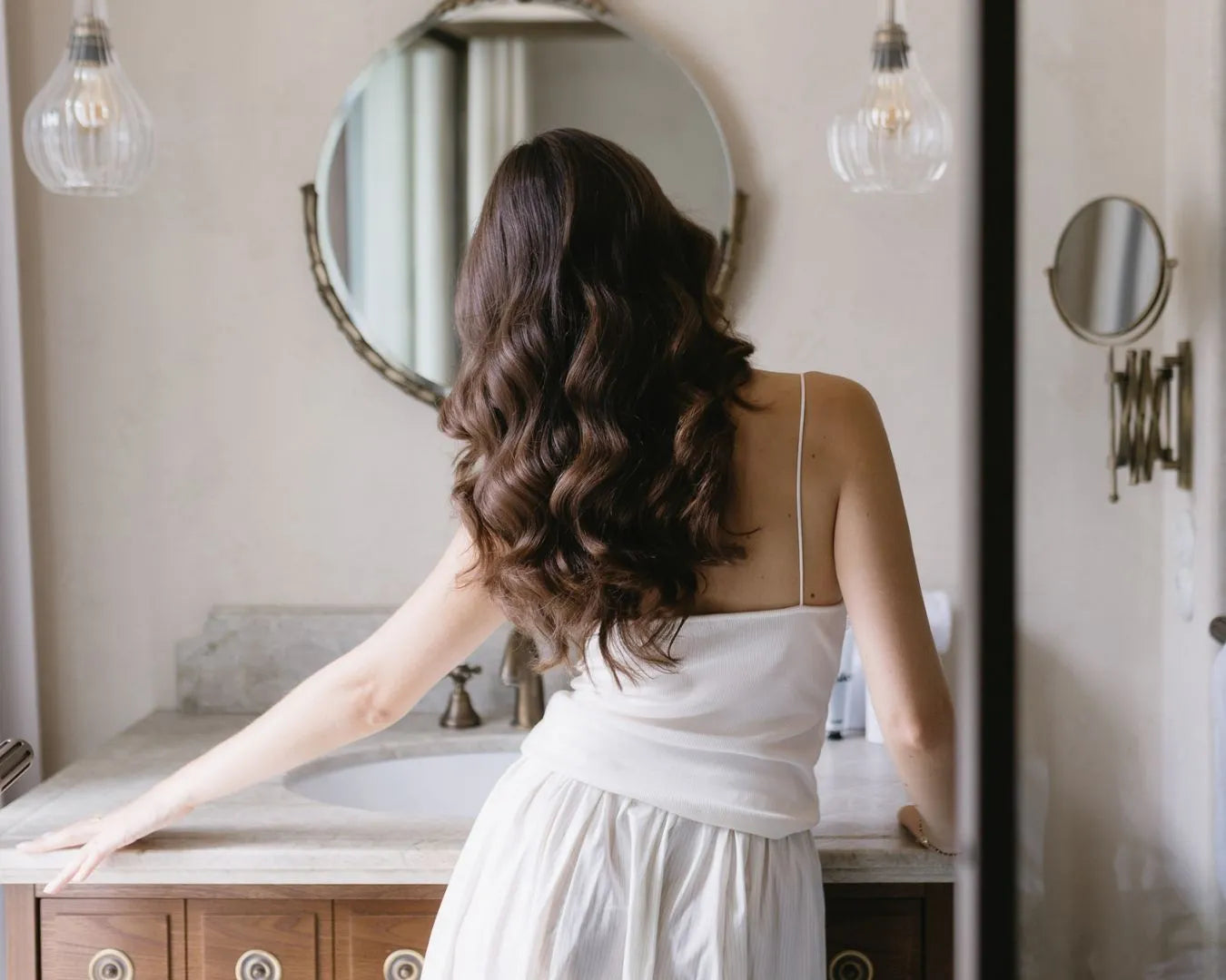 braunes, langes gelocktes Haar von hinten fotografiert in luxuriösen Badezimmer