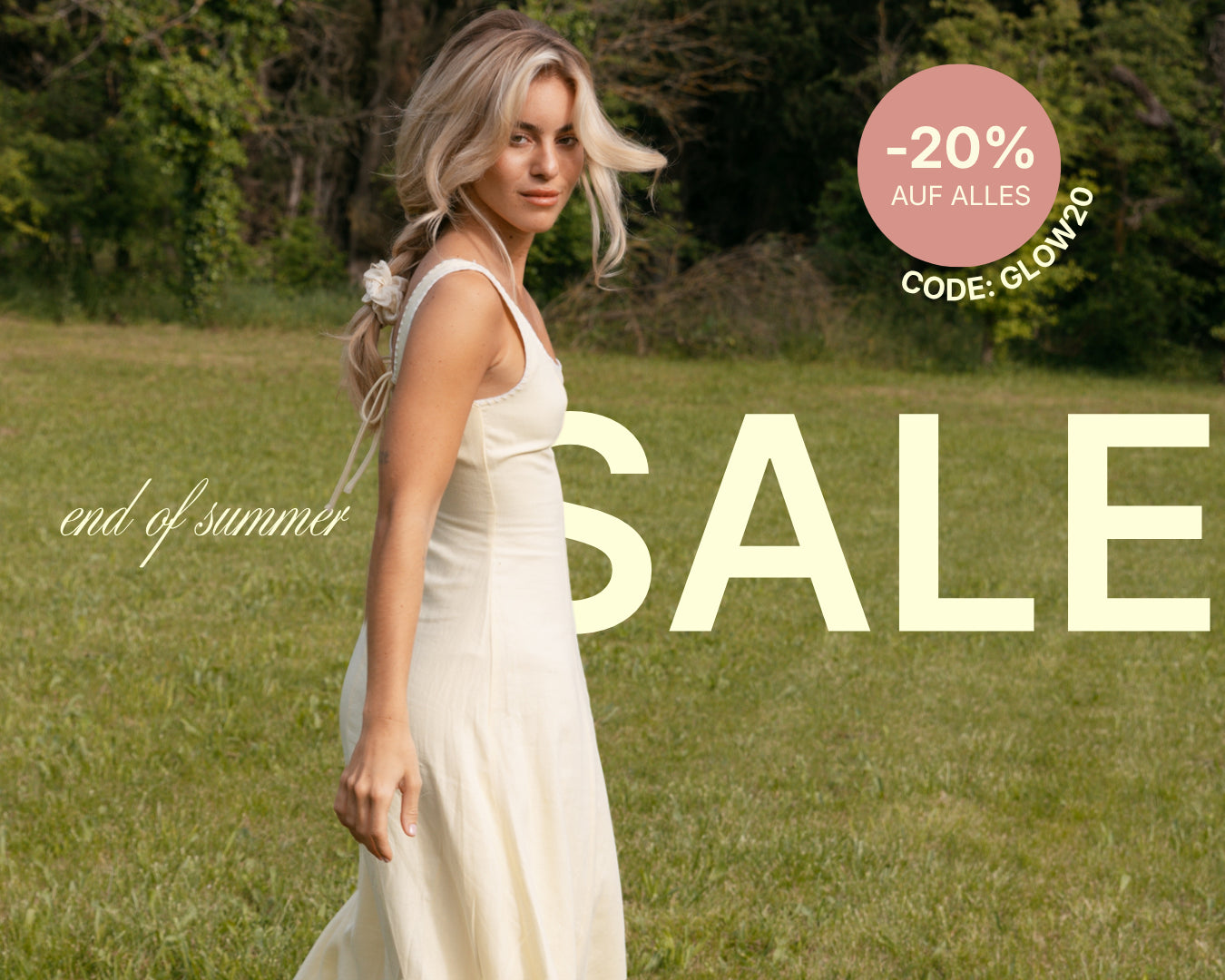 feschi end of summer sale. Blondes Model läuft in weißem Kleid über grüne Wiese und schaut in die Kamera