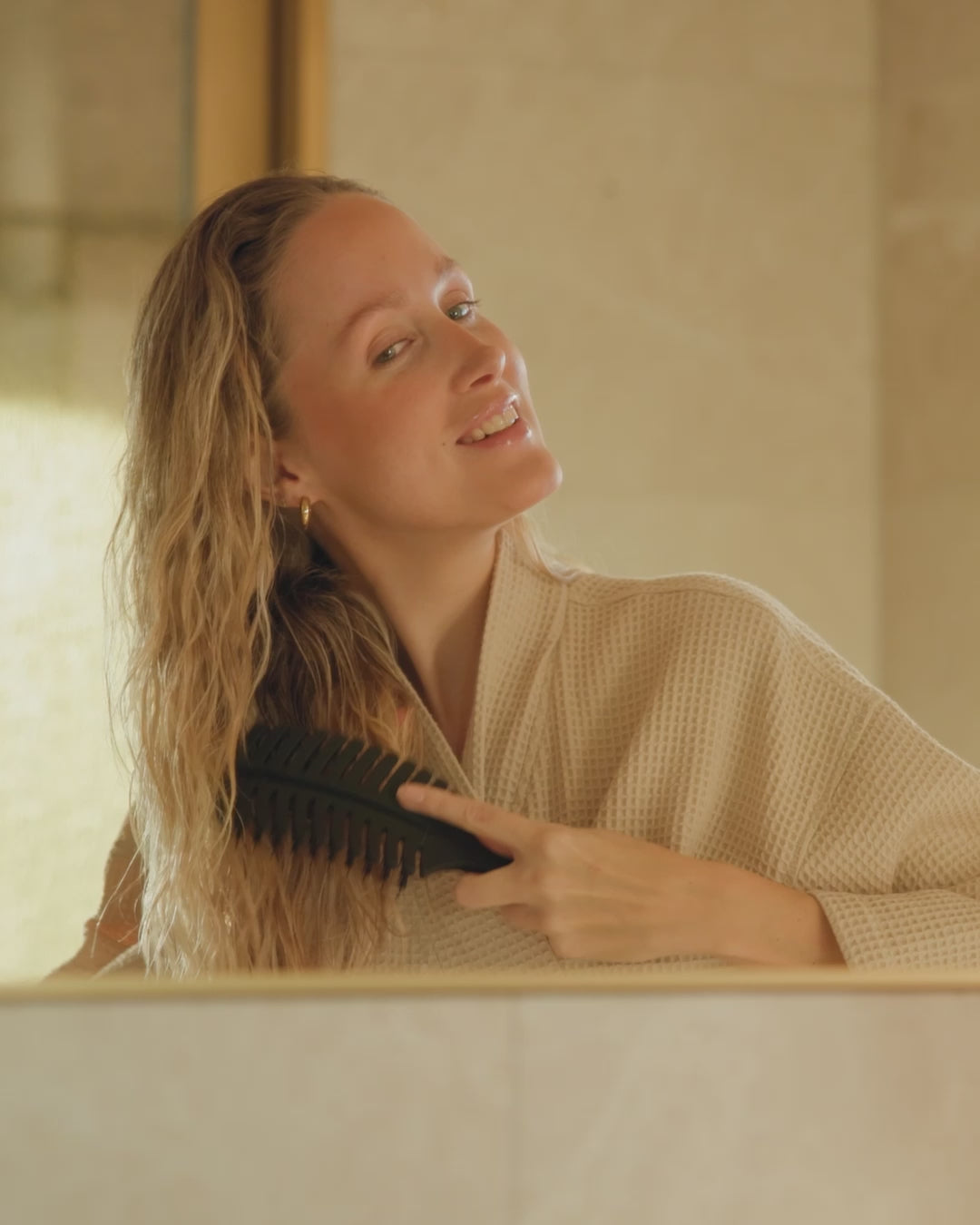 Eine blonde Frau kämmt ihre nassen Haaren mit der feschi Hair Brush