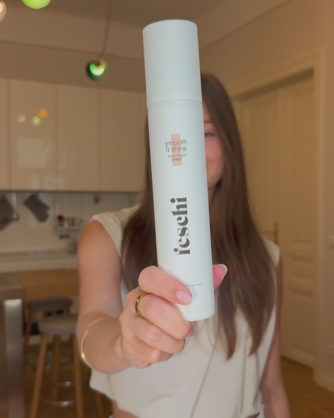 Frau schüttelt Anti Frizz Spray von feschi