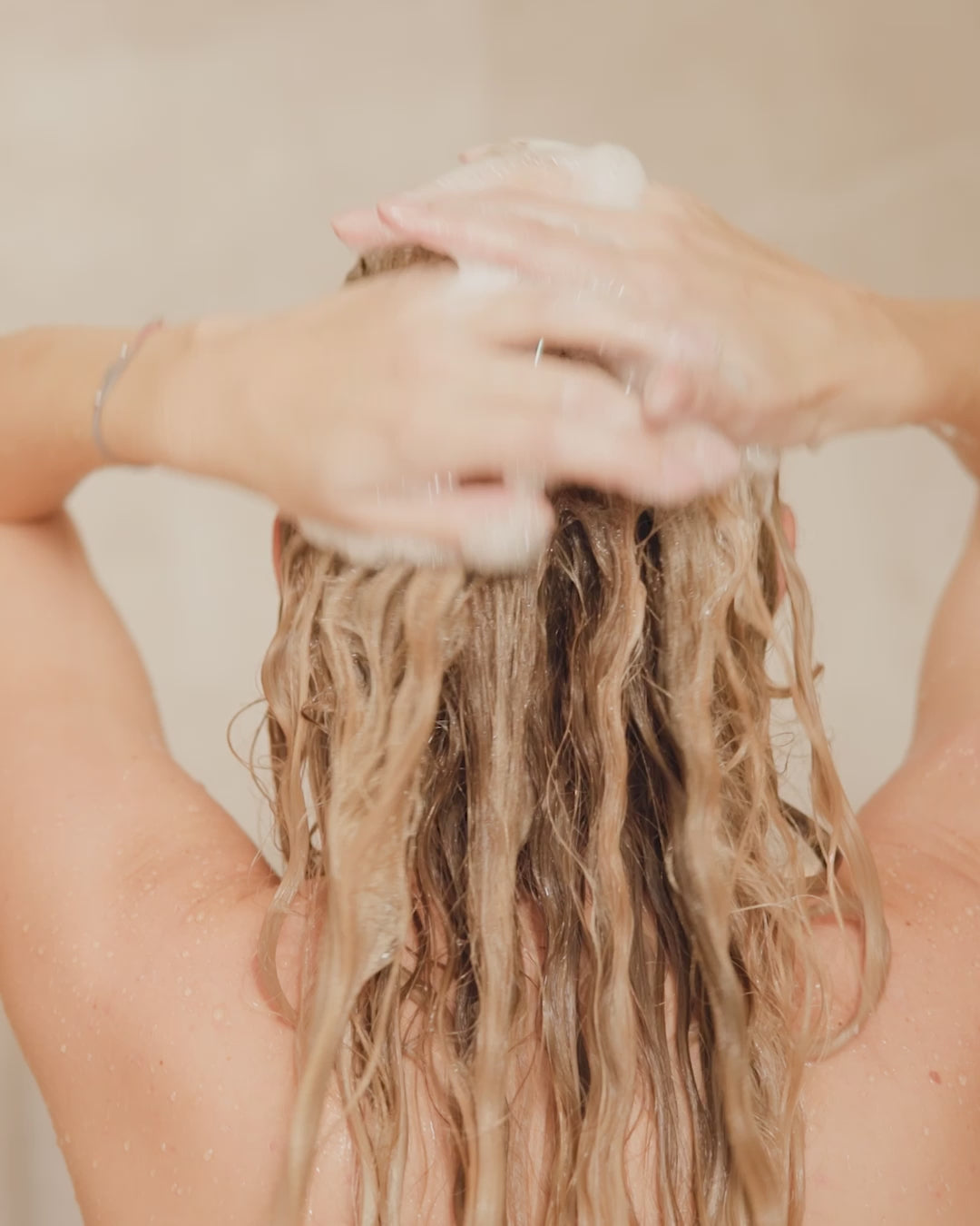 Frau schäumt Shampoo in Haaren auf
