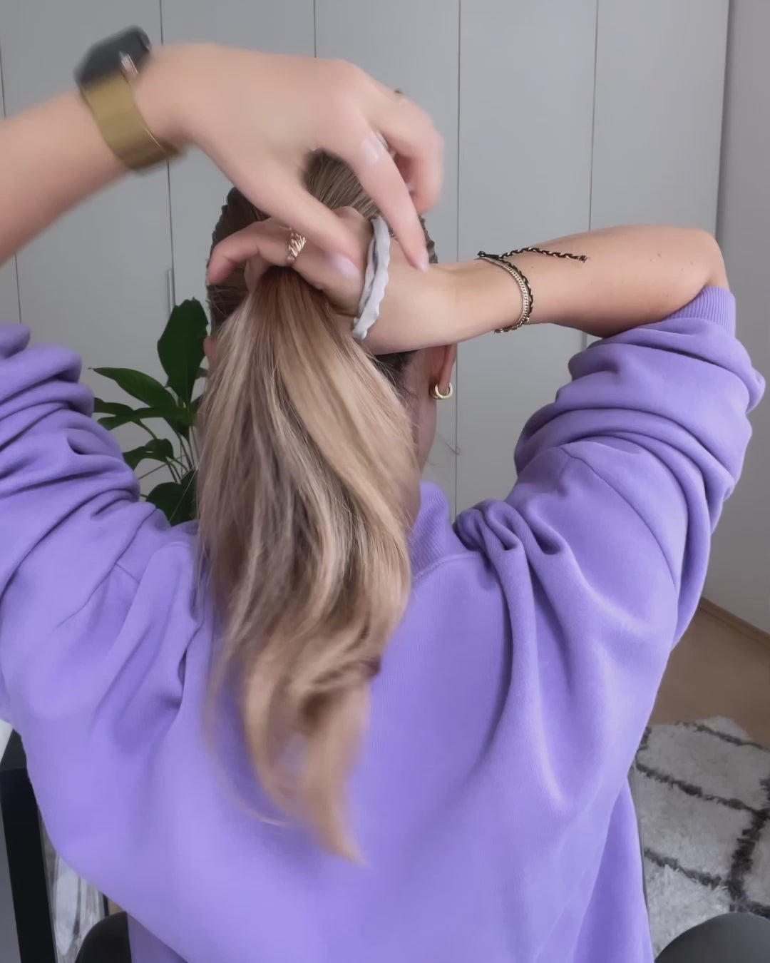 Frau bindet sich die Haare zu einem Pferdeschwanz zusammen