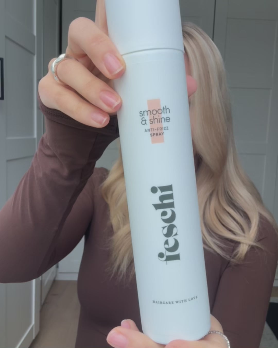 Video, wo sich eine Frau das Anti Frizz Spray von feschi in die Haare sprüht