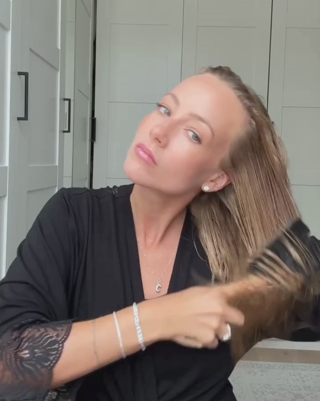Frau bürstet sich nasse Haare und föhnt Haare reicht an