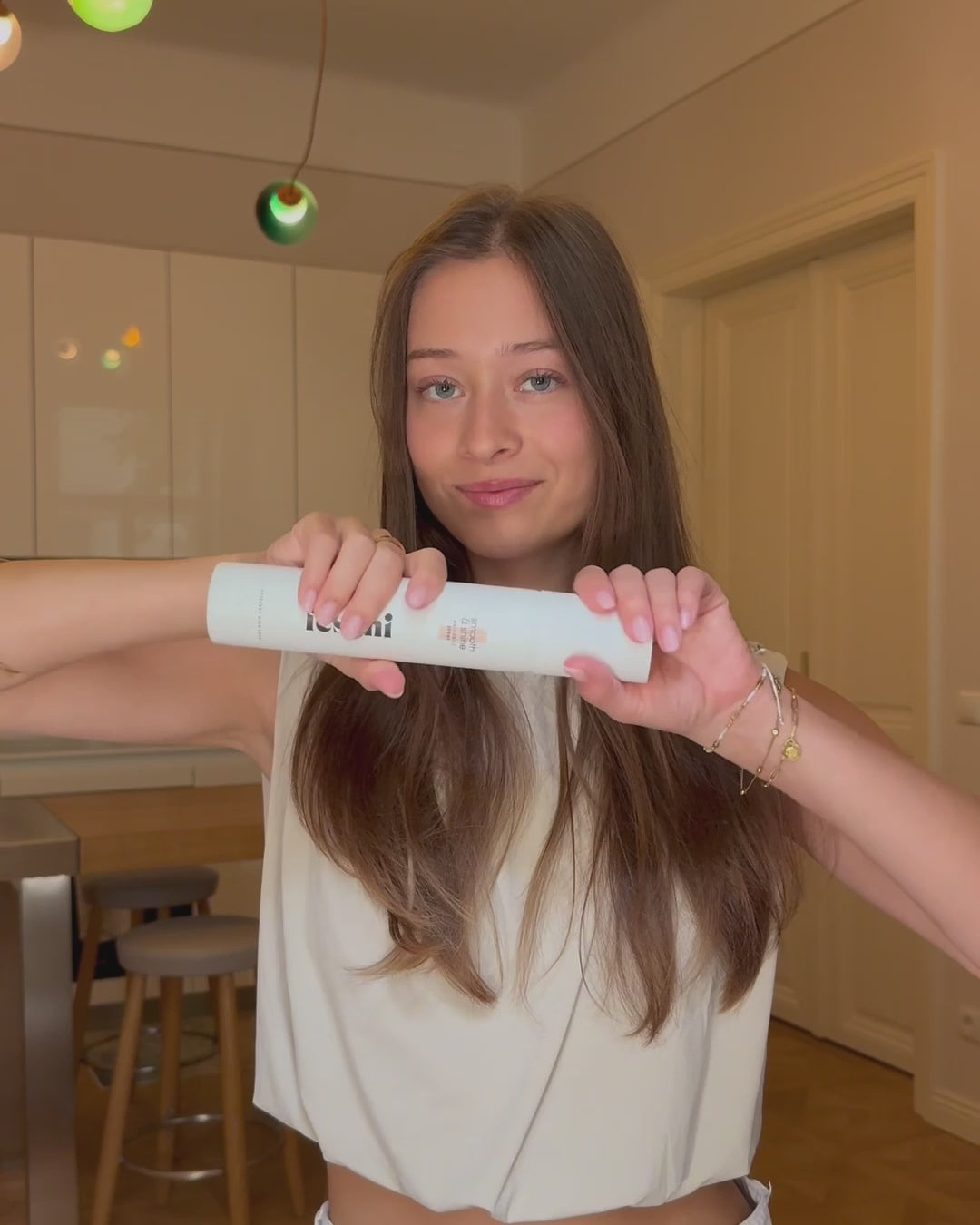 Frau sprüht sich Anti Frizz Spray von feschi in trockene Haare