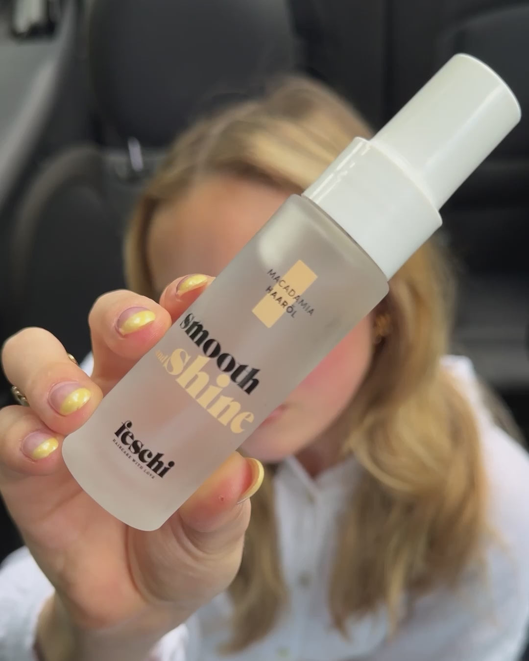 Frau sitzt in Auto und wendet das Haaröl von feschi an