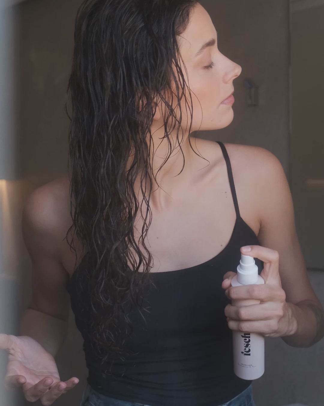 Frau wendet das daily dose Pflegespray im nassen Haar an und knetet es in ihre Haare ein