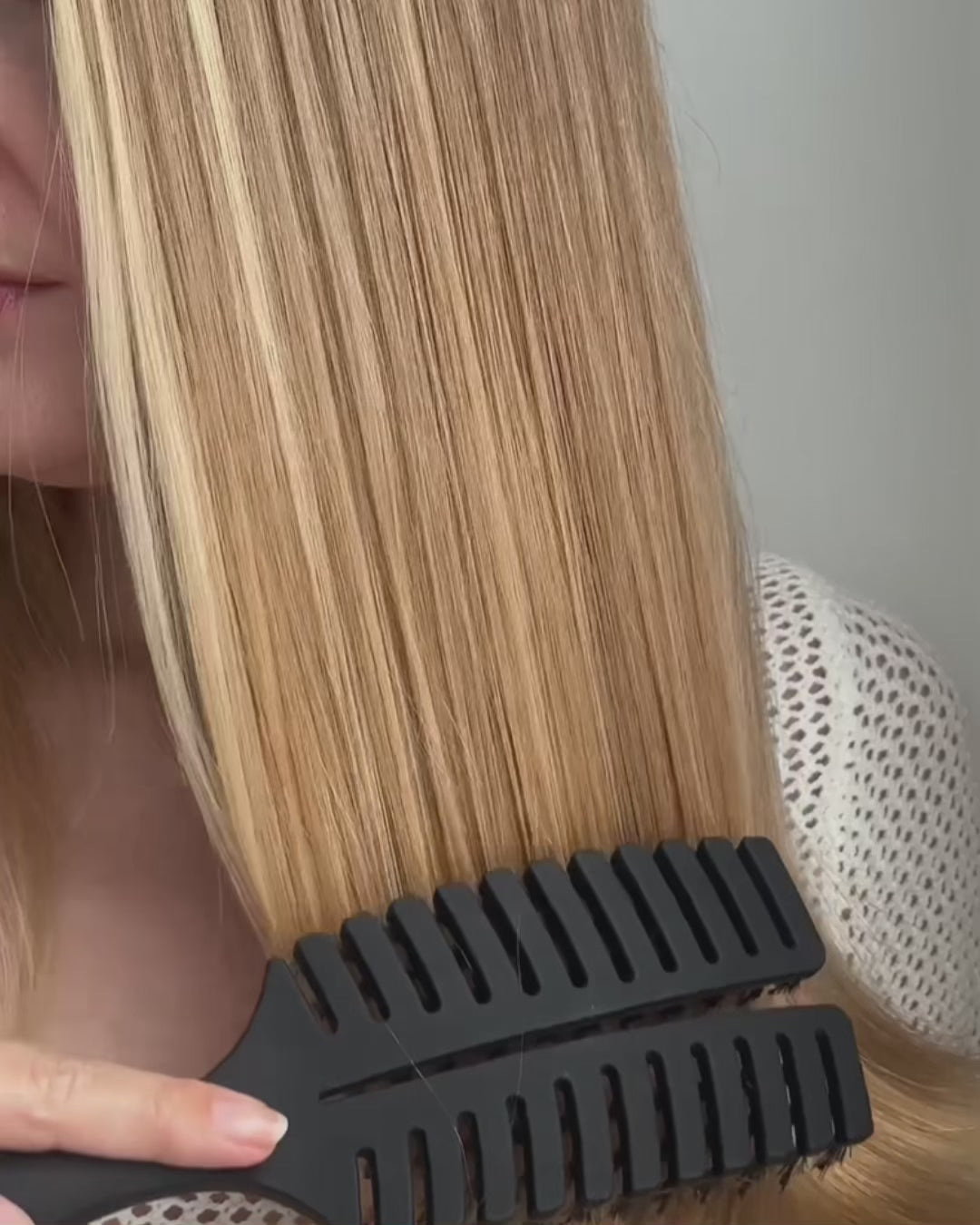Video, wo sich eine blonde Frau, die Haare mit der feschi Hair Brush bürstet