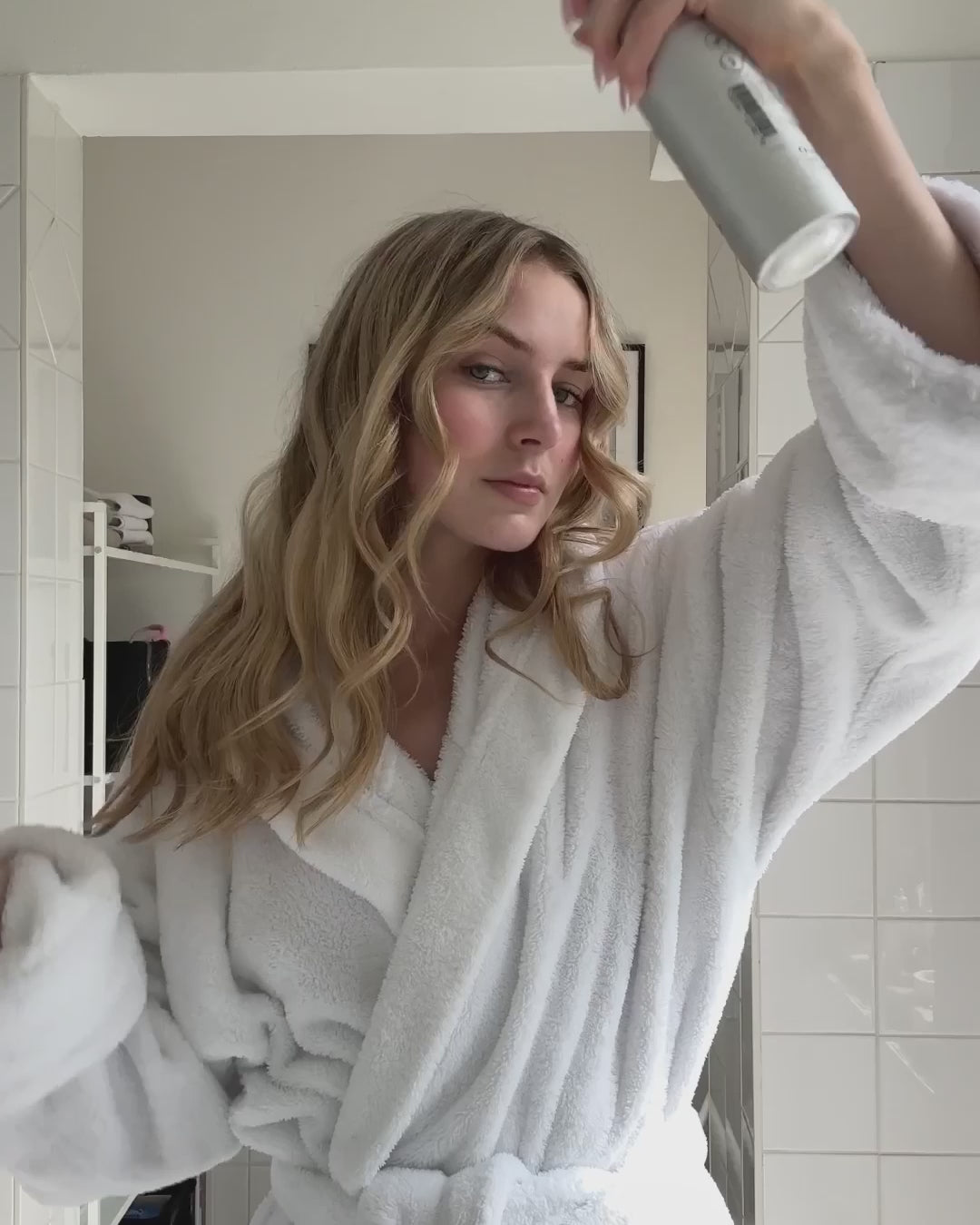 Frau sprüht sich Haarspray von feschi auf Locken zur Festigung