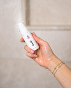 Conditioner in Reisegröße wird in Wasserstrahl gehalten