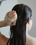 Person mit dunkelbraunen, nassen Haaren verwendet scalp brush von feschi 
