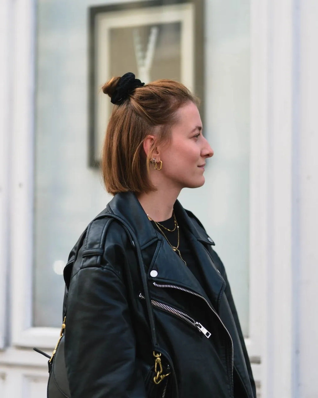 Frau seitlich mit kurzen Haaren, halbem Dutt, trägt das schwarze Scrunchie von feschi