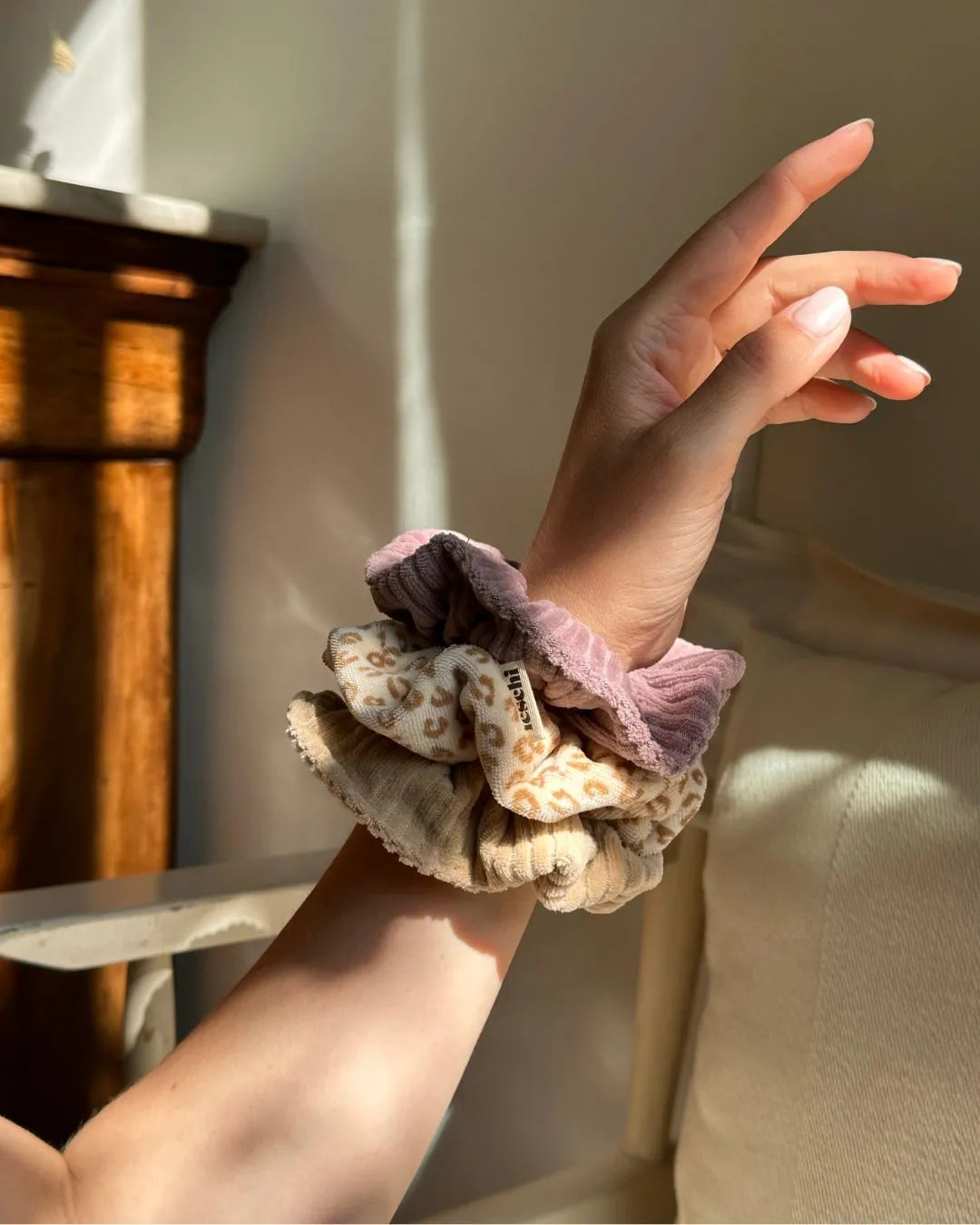 Weiblicher Unterarm mit drei unterschiedlichen Scrunchies wie Armreife getragen