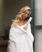 Blonde Frau mit gelocktem Haar zeigt das volume baby Mousse von feschi. Mehr Ansatzvolumen auch in feinem Haar.