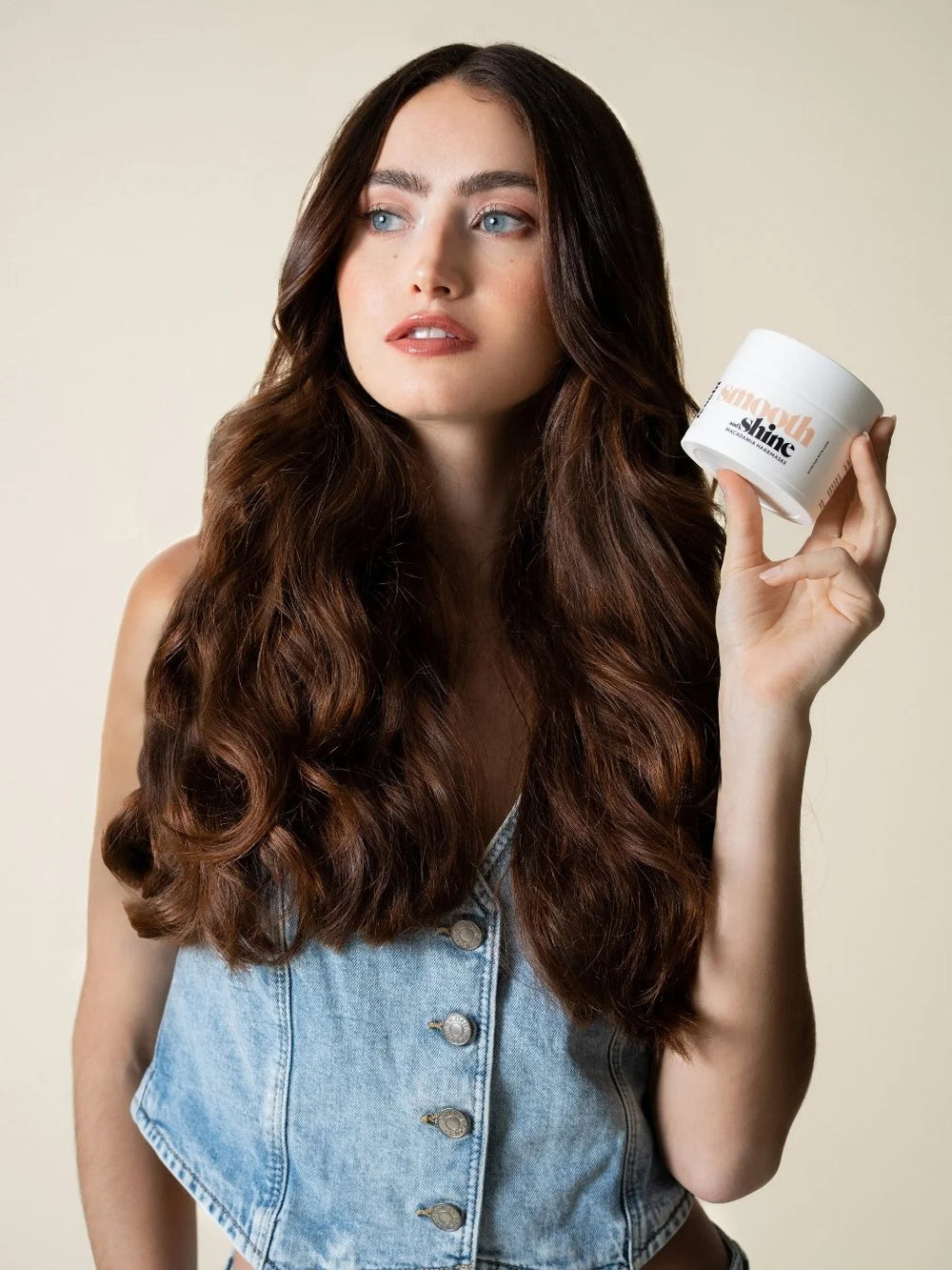 Frau mit dunklen, langen Haaren hält die smooth & shine - Macadamia Maske von feschi in der Hand