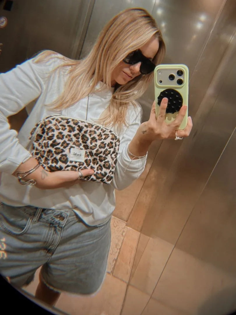 blonde Frau macht Spiegel Selfie in Aufzug mit der feschi Kosmetiktasche Leo. Vintage Filter auf dem Bild