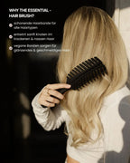 Eine blonde Frau bürstet sich mit der Haarbürste von feschi ihre langen, dicken Haare durch